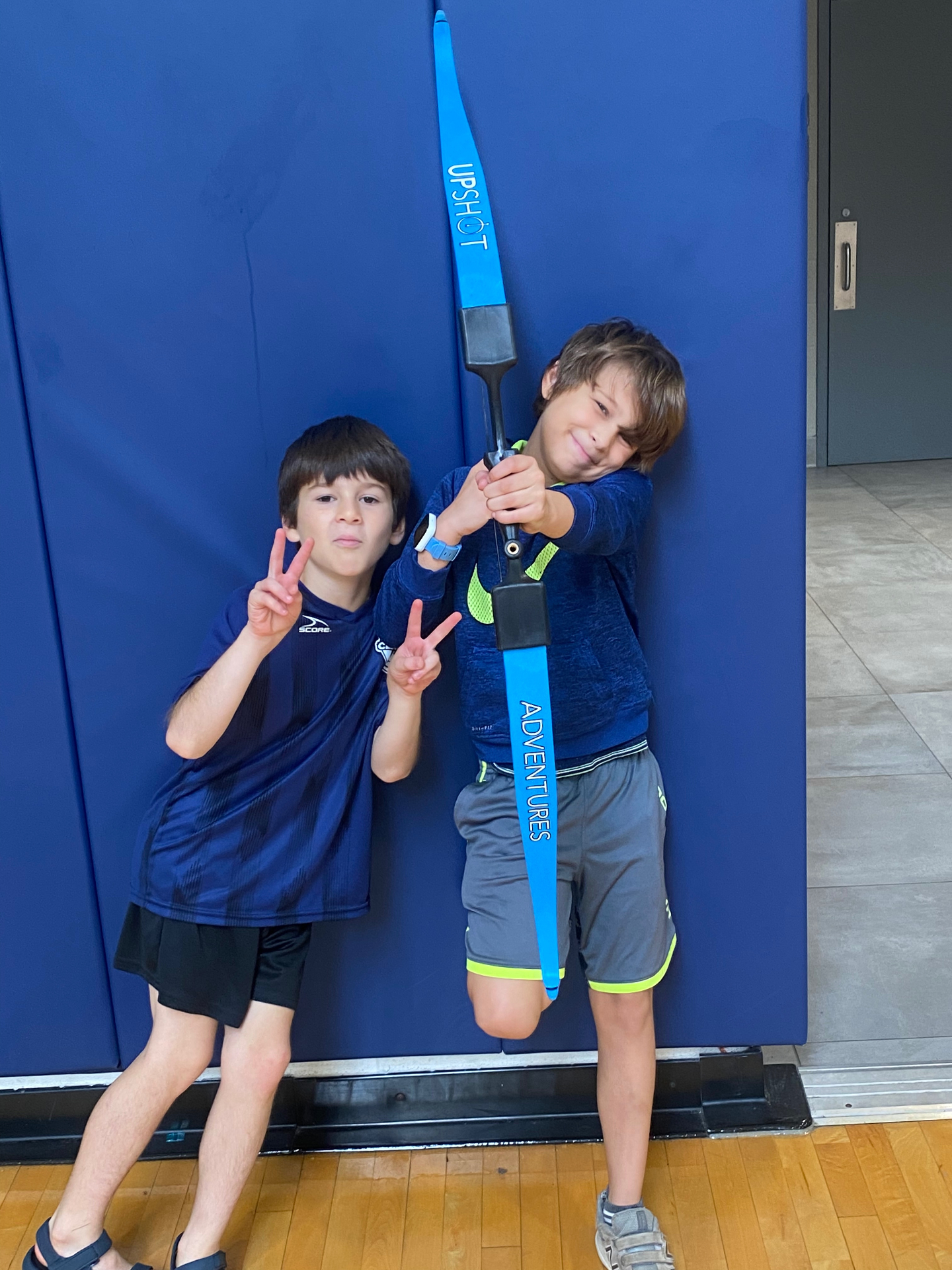 Two kids posing with a foam-tipped bow
