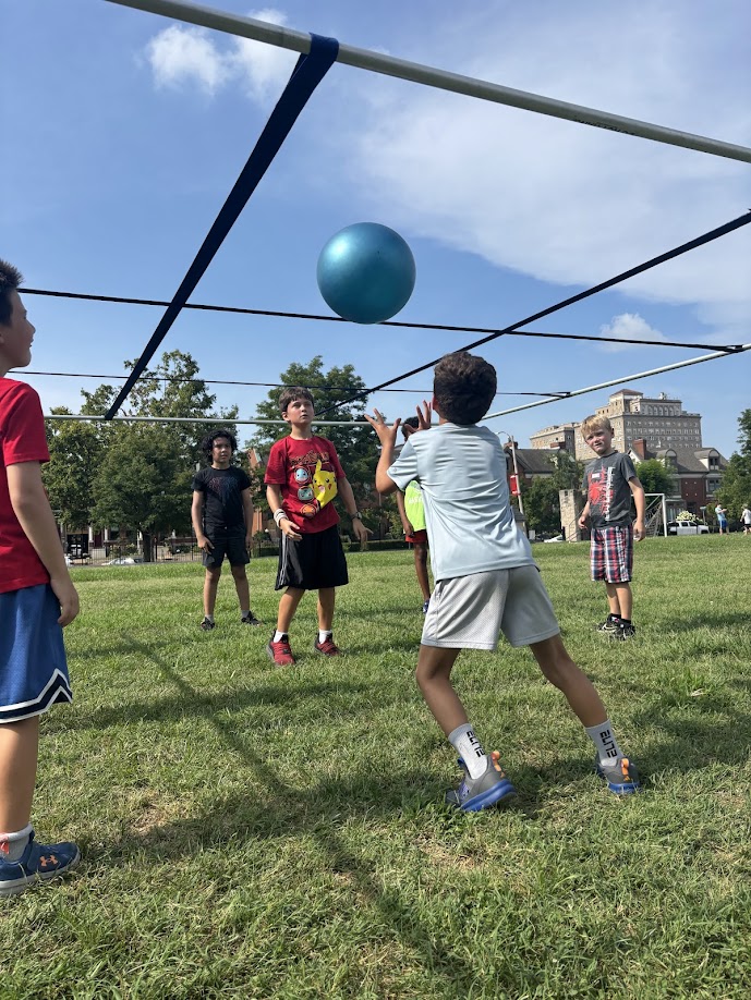 Kids playing 9 Square in the Air outdoors on a grass field