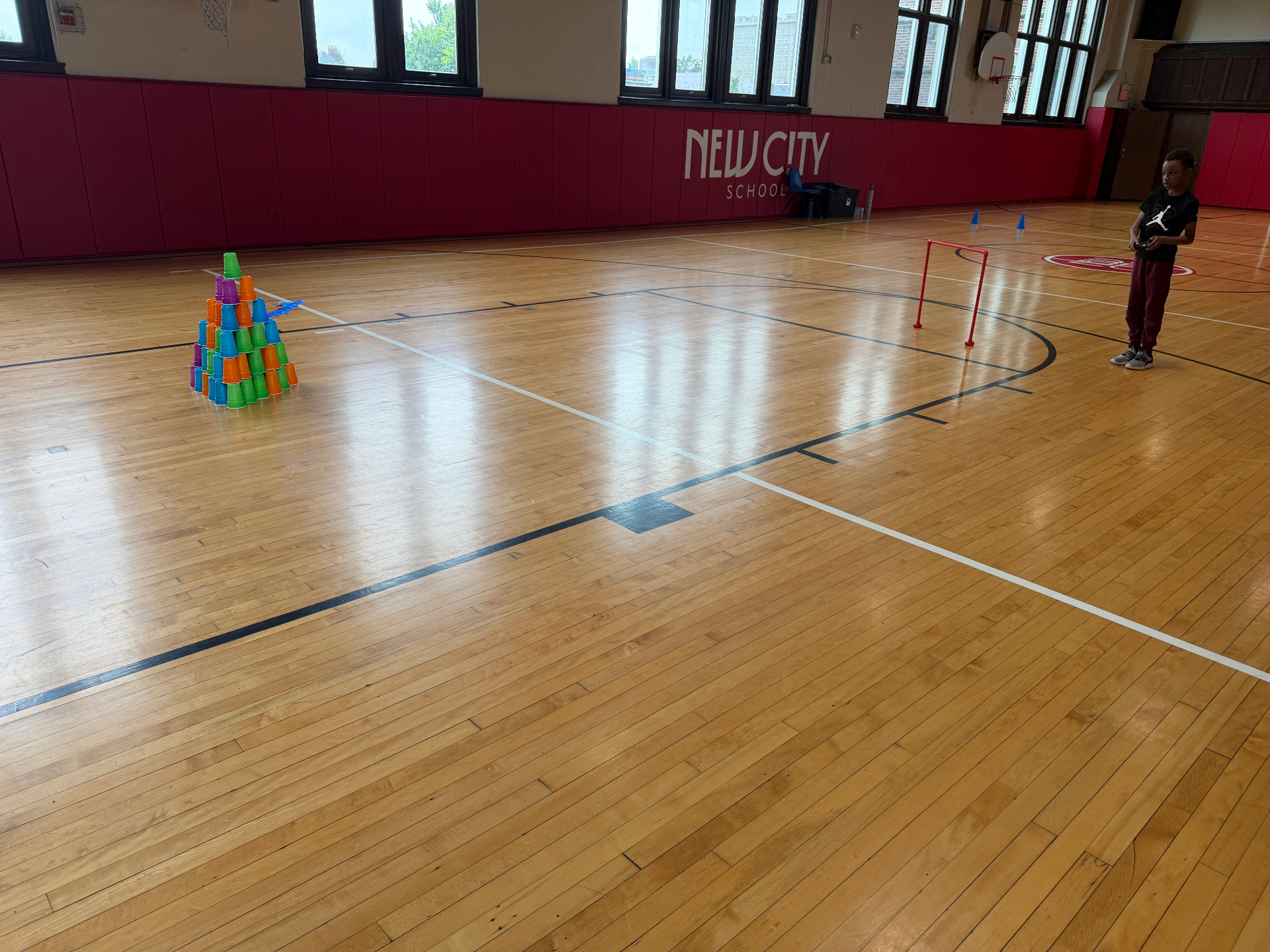 Student piloting a drone through a cup-tower obstacle course at a Recreation Academy drone racing session