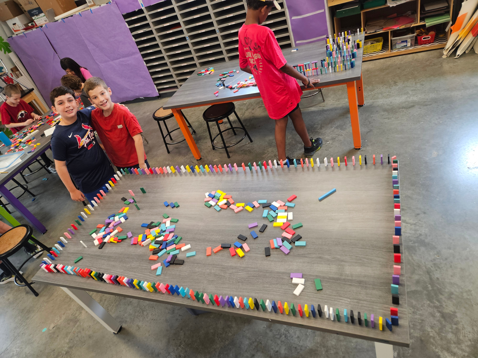 Kids proudly showing off a huge domino build during a Recreation Academy STEM club