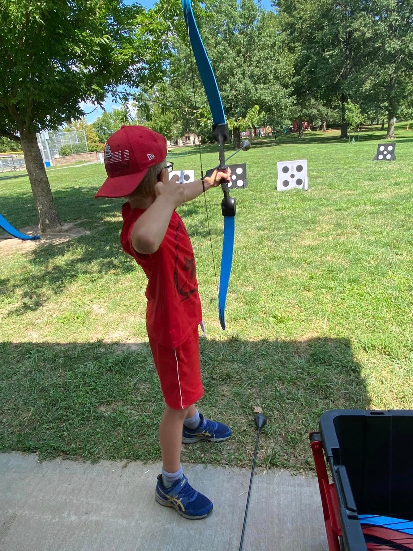 Young archer aiming a foam-tipped bow at outdoor targets